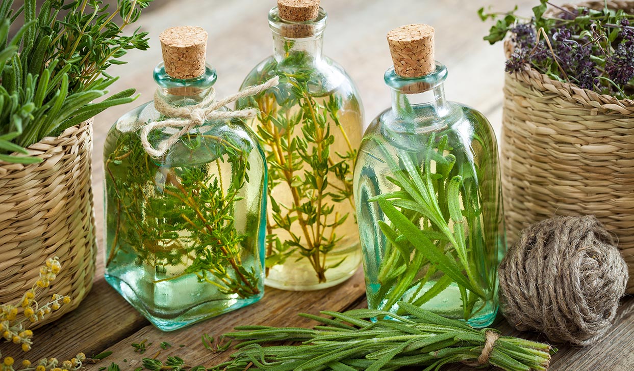 How to make herb infused vinegar, three bottles of vinegar with herbs and cork stoppers.